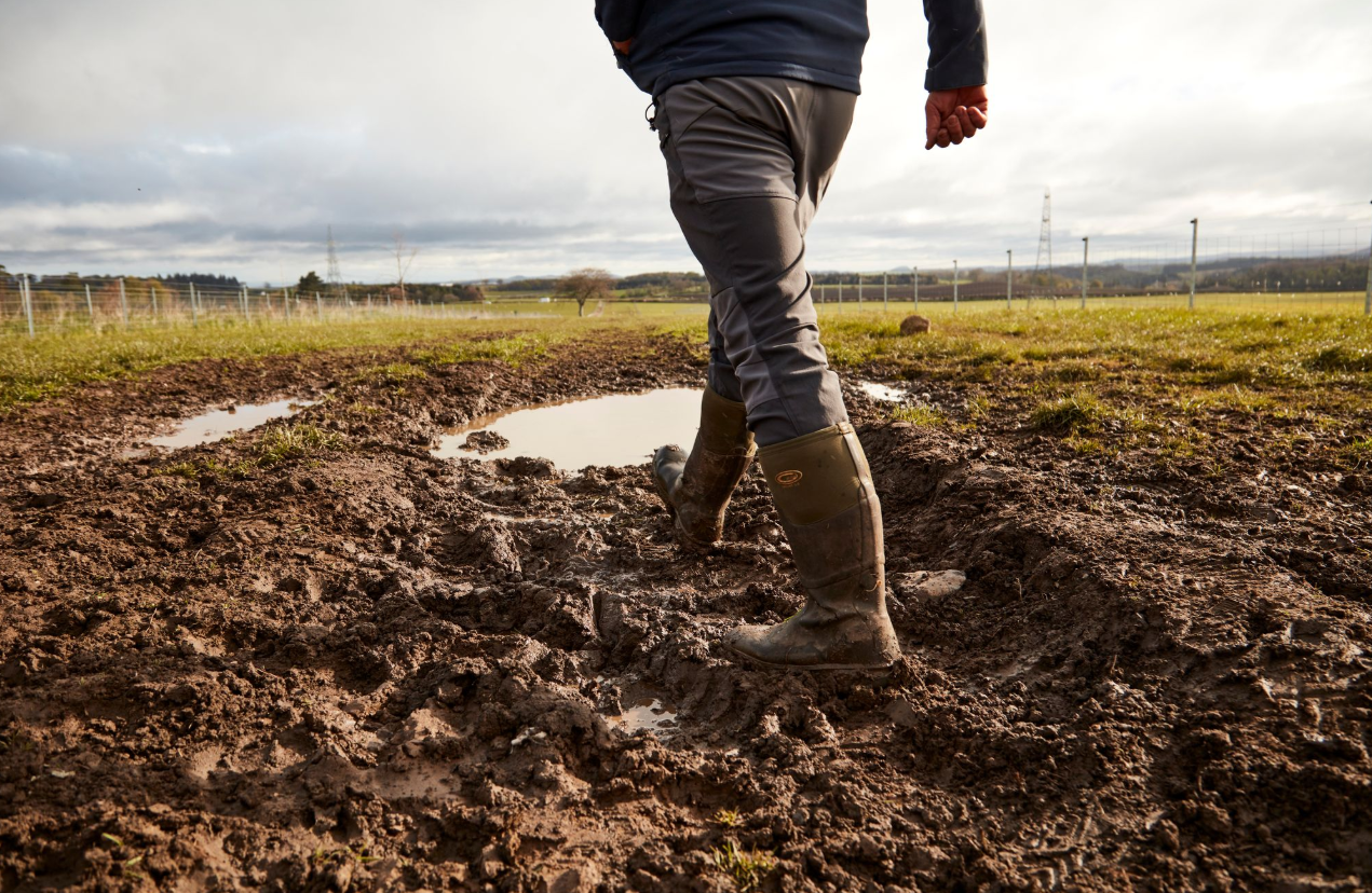 A man in boots crossing a field